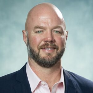 A man in a suit smiling for a head-shot photo